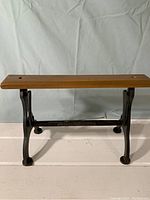 Full front view of the paper towel holder showing wooden shelf and iron base with legs.