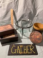 Photo showing the glass vase in black metal footed holder, stacked paper boxes with fruit basket lid, and the slate plaque reading 'GATHER'