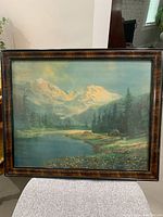 Full view of the framed landscape print showing mountain scene, lake, and forest in a burled wooden frame.