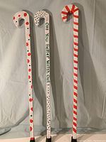 Three decorated solid wood holiday canes with rubber tips, each measuring 33 inches, shown upright against a white backdrop.
