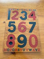 Top-down photo of the complete puzzle assembled on wooden board, showing numbers 0-9 and alphabet border.