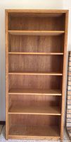 Single wooden bookshelf with five shelves, medium brown wood, adjustable shelves, no visible damage.