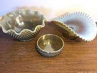 Overall view of three olive green Fenton glass bowls with popcorn pattern displayed on a wooden surface
