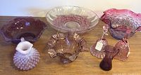 Full lot photo showing bowls, pitchers, bells, and lamp glove on wooden surface