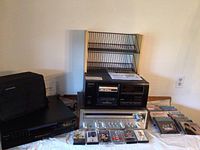 Overall view of all audio equipment including a Pioneer stereo receiver with cassette deck, two Sony CD players, and cassette tapes on a table.