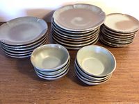 Group of all plates and bowls stacked on wooden surface