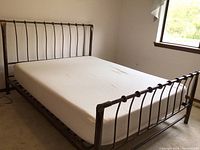 Angle view of queen bed frame with mattress from foot and side
