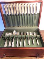 Open wooden chest showing 14 knives secured in lid clips and bottom slots for other flatware.