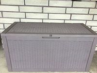 Patio storage box shown closed from front with woven rattan look