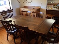 Full view of the dining table with six chairs around it, showing the wood finish and chair style.