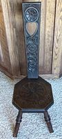 Full view of the birthing stool showing the carved high backrest with floral and heart motifs and the octagonal seat with carved design.