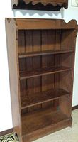 Wooden bookshelf with natural wood finish showing adjustable shelves and curved top edges.