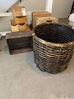 Wide shot showing multiple wicker baskets and wooden storage boxes on carpeted floor near stair railing.