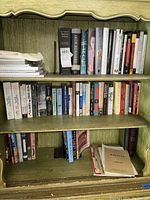 Photo showing a bookshelf with a mix of hard cover and softcover books, Opera programs and printed material (papers, brochures) placed on shelves.