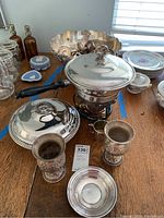 Overall view of assorted silver items on table including chafing dish, punch bowl, goblets, mug, dish, beaker, creamer