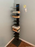Full view of one black metal designer bookshelf loaded with books, showing its scale and structure.