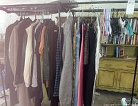 Wide view of assorted ladies jackets, shirts, sweaters, and pants hanging on rack showing variety of colors and styles