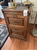 Front and top view of vintage wooden file cabinet showing two drawers with metal handles and label holders.