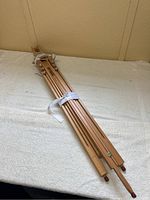 Folded wooden artists easel showing length and bundled with fabric strap.