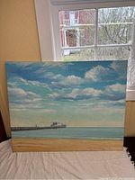 Full frontal view of watercolour painting on canvas showing seascape with ship, sandy beach, sea, and cloudy sky.