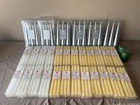 Top view of the entire lot showing white, yellow, silver taper candles, two green rounded candles and holiday pillar candles all in original packaging.