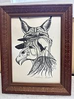 Framed Indigenous-themed black ink drawing illustrating a Native American profile with bird feathers, eagle head overlay, and wolf ears, signed by artist Norman Knott.