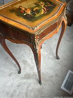 Side view showing curved legs, metal ornamental details at corner, and wear on veneer edges.