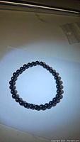 Photo of natural black onyx bead bracelet laid flat on a white surface, showing entire bracelet shape and bead uniformity.