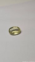 Photo showing oval cut lemon citrine gemstone from a top angle lighting up its facets and light yellow color.