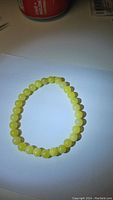 Photo of the natural lemon jade stretchy bracelet showing bright yellow round beads on a white surface.
