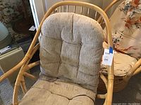 Front view of bamboo chair with oatmeal cushioned seat showing tufted design and light wear marks.