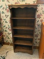 Front view of the small wooden book shelf showing five fixed shelves with scalloped top and bottom edges