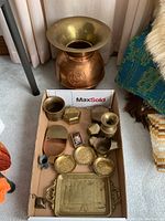 Photo showing all items in the lot arranged in a cardboard box and the brass spittoon positioned behind.