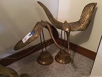 Two brass crane bird sculptures positioned side by side showing overall design and size comparison.