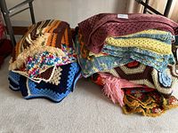 Two stacks of assorted crochet throw blankets showing various colors and patterns, with some having fringed edges.