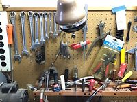 Wide view of pegboard with multiple wrenches, sockets, screwdrivers and other tools hanging and resting on a shelf