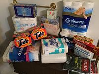 General lot overview showing bulk paper products, detergent, and storage boxes in basement space.