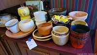 Overview of about 20 assorted pots and planters with various sizes, colors, and patterns, showing the variety included in the lot.
