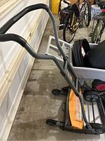 View of the mower handle with ergonomic black grip and sturdy gray frame.