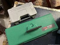 Closed view of two plastic carrying cases: a green Sears Craftsman case and a gray case labeled 25pcs rubber sanding drum set.