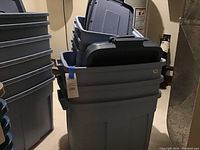 Stack of blue Rubbermaid storage totes with lids, showing three large totes and three smaller totes in basement setting.