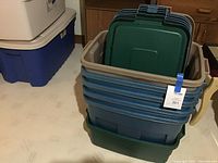 Stack of 6 Rubbermaid storage totes including 5 large blue ones and 1 medium green one at bottom with lids on top.