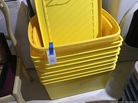 Stacked set of large yellow Rubbermaid storage totes with lids nested inside.