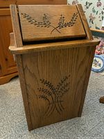 Full view of oak garbage can showing carved wheat sheaf design on front and swing top lid.