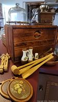 Overall view showing wooden bread box, glass dome, hourglass, coffee mill, ceramic cruets and shakers, and wooden kitchen tools on table