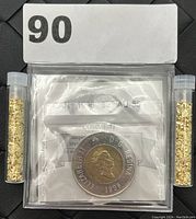 Front side of the 1996 Canadian $2 coin with Queen Elizabeth II and two small vials of gold flakes on both sides.