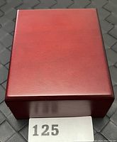 Closed reddish wooden display box for the coin.