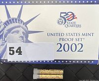 2002 United States Mint Proof Set box alongside two small glass vials containing gold flakes