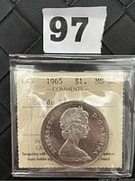 Obverse side of the encapsulated 1965 Canadian $1 silver dollar coin with Queen Elizabeth II profile and ICCS grading card showing MS-60 grade and comments.