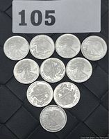 Top view of 10 Silvertowne fractional silver coins arranged in a triangular shape on a black woven surface, with lot number 105 tag above.